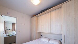 Un dormitori amb llit, armari de fusta i una porta que dona a un bany.