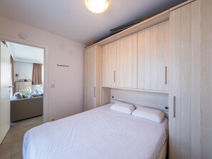 Ein Schlafzimmer mit Bett, Holzschrank und einer Tür zu einem Badezimmer.
