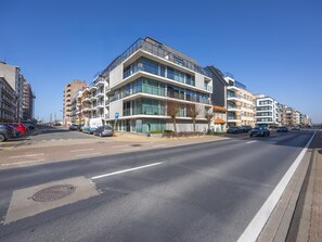 Ein modernes, mehrgeschossiges Gebäude mit Parkplatz davor.