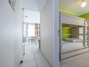 A room with a bunk bed, a small table with chairs, and a glass door leading to another room. - Apartment within walking distance of the beach (Middelkerke)
