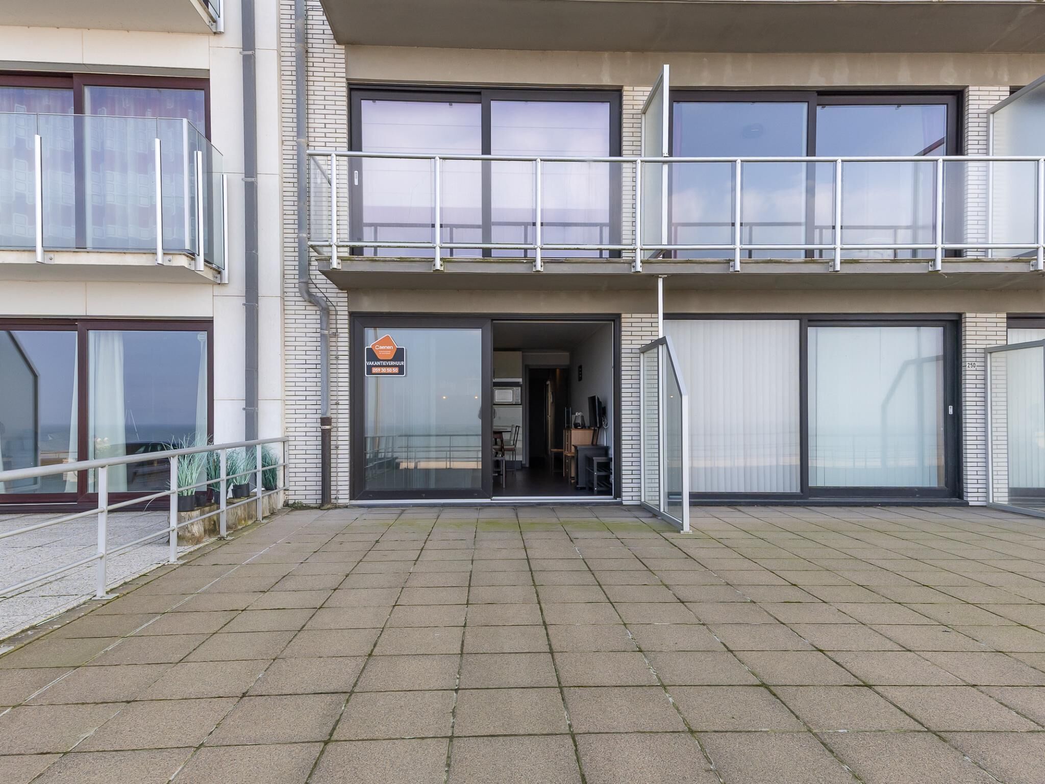 A modern building with a glass entrance, a balcony, and a sign indicating a vacancy.
