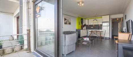 A modern apartment with a balcony, a dining area, a kitchen, and a living room.