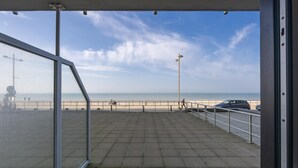 Vista desde un balcón sobre una playa, con cielo despejado.