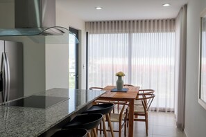 Eine moderne Küche mit Granit-Arbeitsplatte, Edelstahlgeräten und einem Essbereich mit Holztisch und Stühlen.