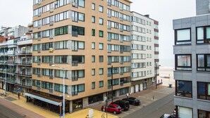 A multi-story hotel with a modern architectural design, featuring a ground-level restaurant and a parking area. - Apartment on the 6th floor with sea view (Middelkerke)