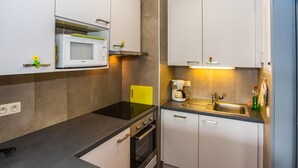 A modern kitchen with white cabinets, a black countertop, a built-in microwave, a coffee maker, and a sink. - Apartment on the 6th floor with sea view (Middelkerke)