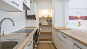 A modern kitchen with stainless steel appliances, wooden countertops, and a small dining area with a view of the sunset. - Stunning apartment with phenomenal sea view (Middelkerke)