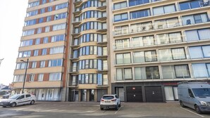 Un edificio residenziale a più piani con balconi, un'area di parcheggio e un furgone parcheggiato davanti.