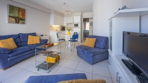 Un soggiorno moderno con due divani, una TV e un'area pranzo con tavolo e sedie.