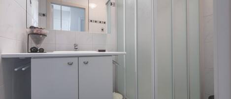 A modern bathroom with a shower, a sink with a mirror, and a toilet.