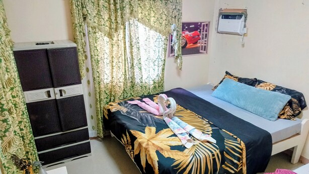 A bedroom with a bed, a small table with a telephone, a wall-mounted air conditioner, and a decorative statue.