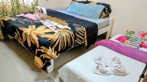 A hotel room with two beds, each with a different patterned bedspread. There is a small rug on the floor and a single pillow on one of the beds.
