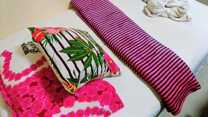 A neatly made bed with a striped pillow, a floral pillow, and a towel.