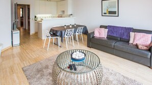 A modern living room with a glass coffee table, a sofa, and a dining area with chairs. - Cozy apartment near the sea (Middelkerke)