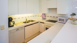 A modern kitchen with white cabinets, a Bosch dishwasher, a microwave, and a sink. - Cozy apartment near the sea (Middelkerke)