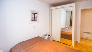 A bedroom with a bed, a wardrobe, a bedside table, and a mirror. - Cozy apartment near the sea (Middelkerke)