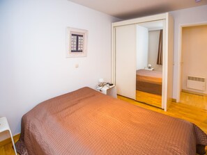 Een slaapkamer met een bed, een kledingkast, een nachtkastje en een spiegel.