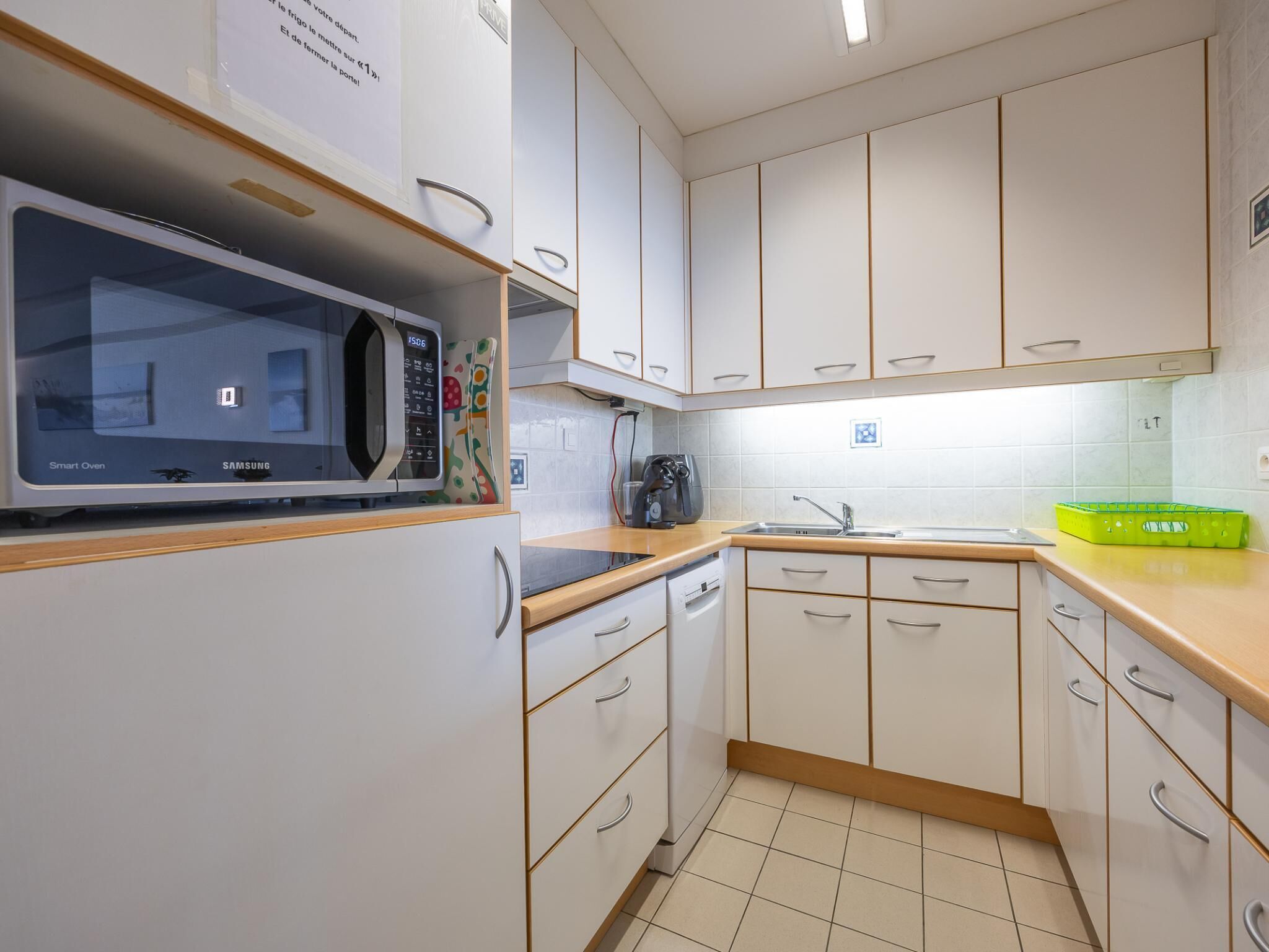 Una cocina moderna con armarios blancos, un microondas, un hervidor y un lavamanos.