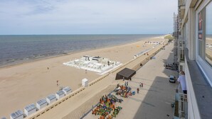 Vista sulla spiaggia dal balcone, con area piscina, ombrelloni e torretta di salvataggio.