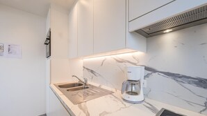 Una cucina moderna con un piano di lavoro in marmo, lavello in acciaio inossidabile e una macchina da caffè.