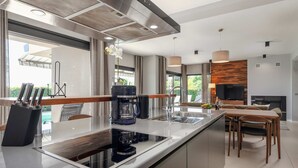 A modern kitchen with a central island, stainless steel appliances, and a dining area with wooden furniture. - Villa Rose (100541-K1) - Porec (Porec)