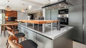 A modern kitchen with a central island, stainless steel appliances, and a dining area with wooden chairs. - Villa Rose (100541-K1) - Porec (Porec)