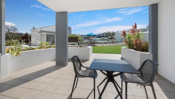 Une terrasse extérieure avec une table et des chaises, entourée de jardinières et offrant une vue sur le paysage urbain.