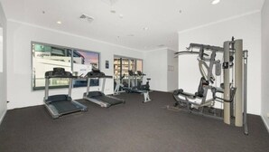 Une salle de sport équipée de tapis de course, d’un vélo d’appartement et d’une machine de musculation.