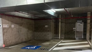 Un parking avec un espace d’accueil, un ascenseur et une place de stationnement réservée aux personnes handicapées.