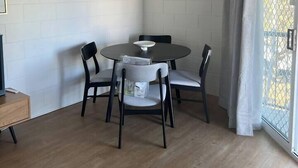 A dining area with a round table, four chairs, a ceiling fan, and a window with curtains. - 1 Bed Apartment on Henry (West End)