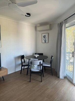 A dining area with a round table, four chairs, a ceiling fan, and a window with curtains. - 1 Bed Apartment on Henry (West End)