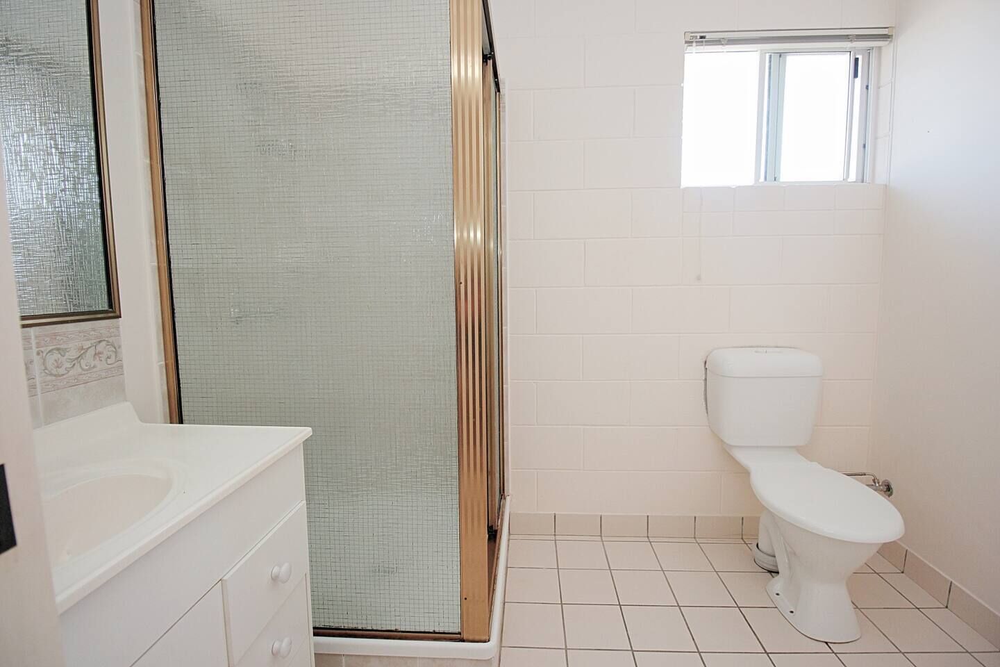 Une salle de bain avec douche, toilettes et lavabo.
