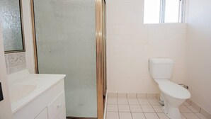 A bathroom with a shower, toilet, and sink. - 1 Bed Apartment on Henry (West End)