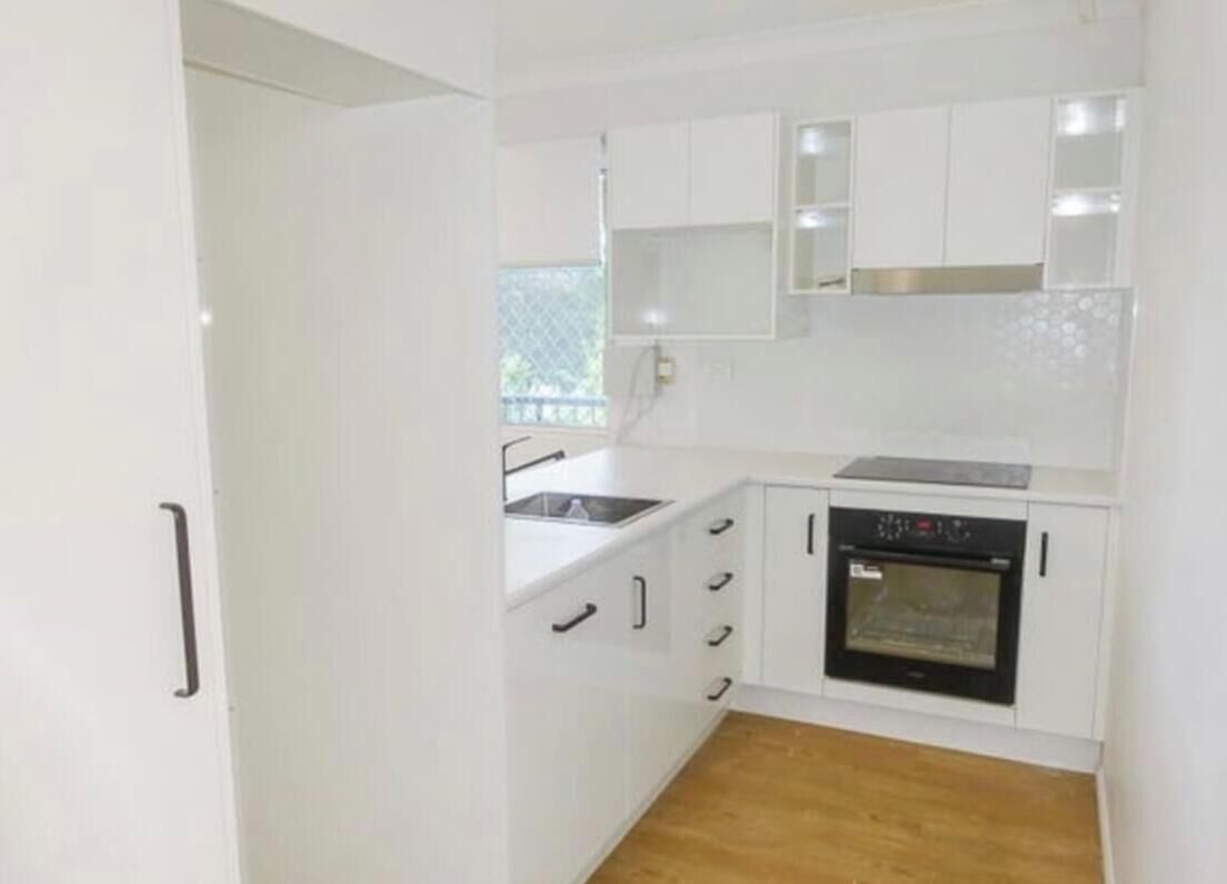 A compact kitchen with white cabinets, a sink, and an oven.