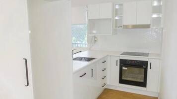 A compact kitchen with white cabinets, a sink, and an oven.