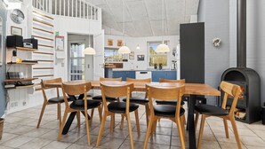 A modern kitchen with a dining area, wooden chairs, a built-in stove, and a staircase. - Super nice holiday home with whirlpool (Højslev)