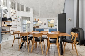 Een moderne keuken met een eethoek, houten stoelen, een inbouwfornuis en een trap.