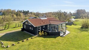 A modern house with a large glass windowed porch, surrounded by a well-maintained lawn and trees. - Super nice holiday home with whirlpool (Højslev)