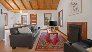 Ein Wohnzimmer mit Kamin, einer Couch, einem Fernseher und einem Essbereich mit Tisch und Stühlen.