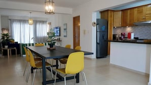 Een moderne keuken met een eetgedeelte, voorzien van een groot schiereiland, gele stoelen en houten keukenkastjes.