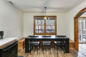 A dining area with a wooden table and chairs, a window with a view of trees, and a ceiling fan. - ‘Raley's Retreat’ w/ Hot Tub: 2 Mi to Dtwn Boone! (Boone)