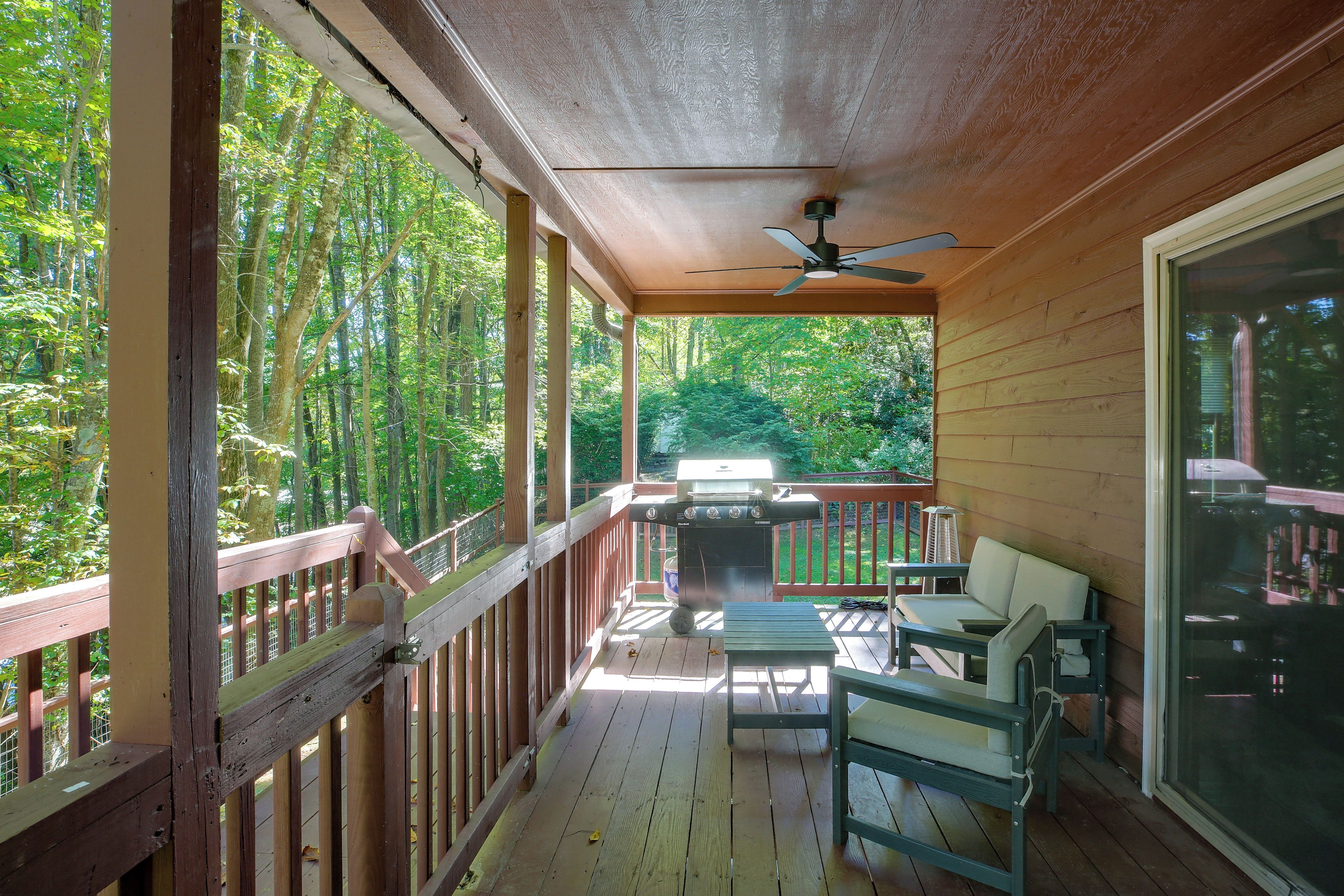 A wooden deck with a ceiling fan, a grill, and outdoor seating.