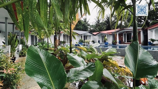 Ein Hotel mit mehreren Zimmern, einem Swimmingpool und üppiger tropischer Bepflanzung.
