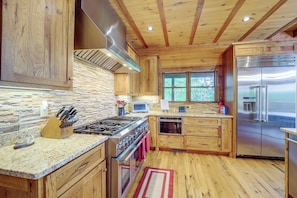 Una cocina con gabinetes de madera, una estufa de acero inoxidable y un refrigerador.