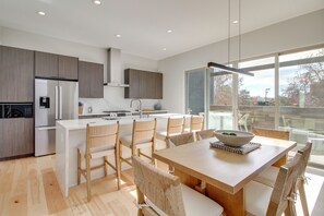 A modern kitchen with a central island, wooden chairs, and a large window offering a view of the outdoors. - Sunnyside View: ABQ Home Near Old Town & BioPark! (Albuquerque)