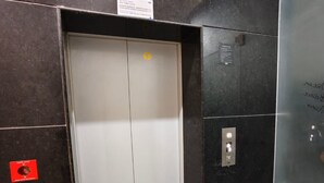 Un ascenseur doté d  ’un panneau de commande, d’un bouton d’urgence et d’une signalétique au-dessus de la porte.