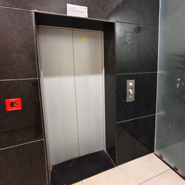 Un ascenseur doté d’un panneau de commande, d’un bouton d’urgence et d’une signalétique au-dessus de la porte.