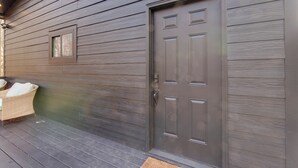 Une façade en bois avec une porte de couleur gris foncé et une petite fenêtre.