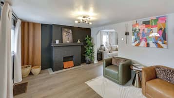 A modern living room with a fireplace, a sofa, a coffee table, and a painting on the wall.