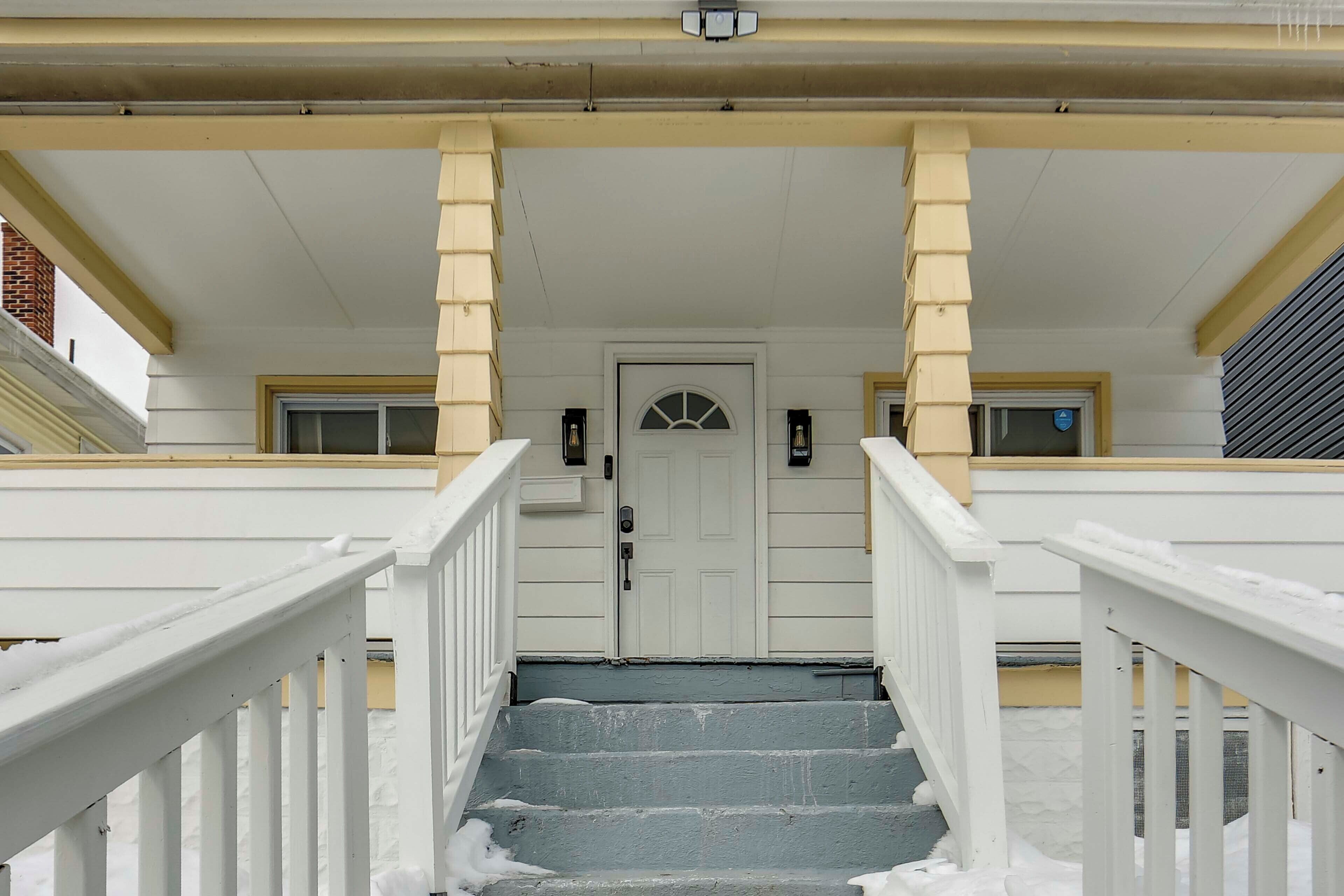 A white staircase with a door at the top, flanked by two windows with black frames.